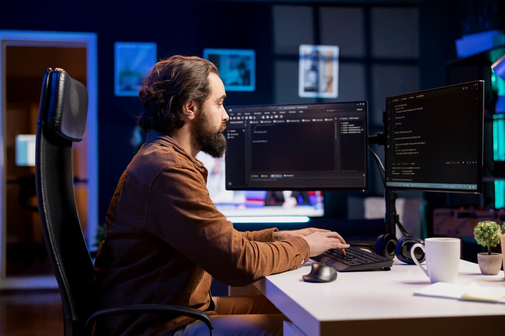 Software developer working on code across multiple screens